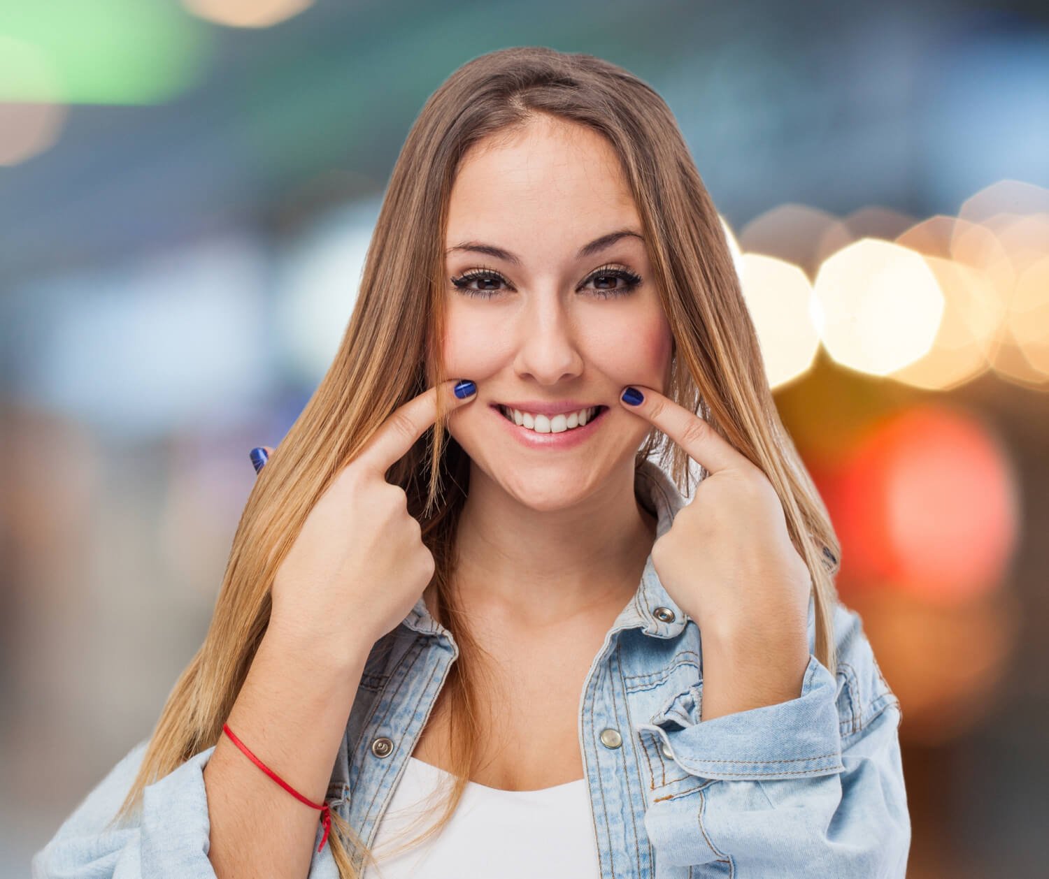 Mulher jovem sorridente apontando para os dentes brancos e alinhados após lentes de contato dental na Pleno Ser em São Bernardo do Campo.
