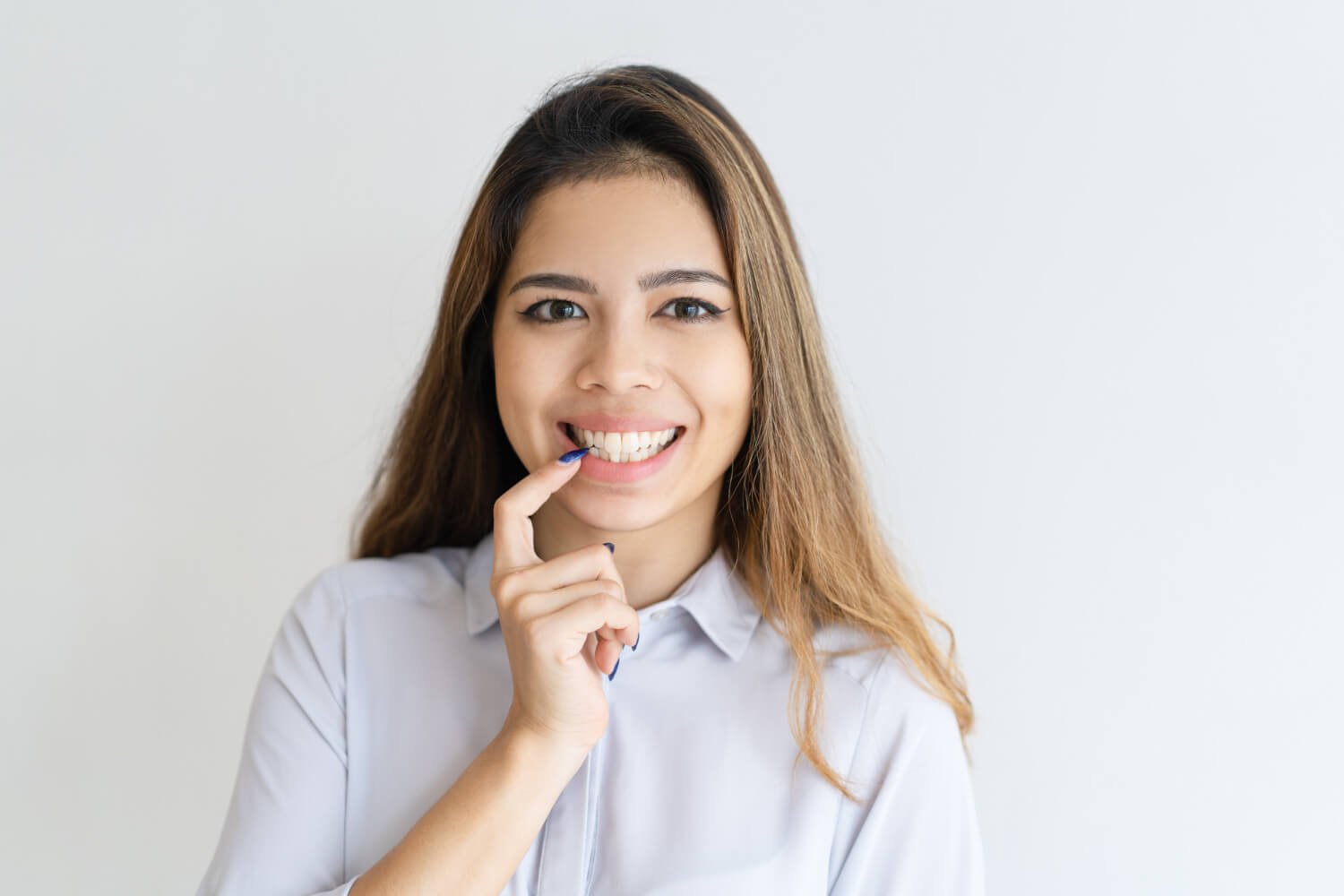 Mulher sorridente aponta para os dentes da frente saudáveis e restaurados na Clínica Pleno Ser em São Bernardo do Campo.