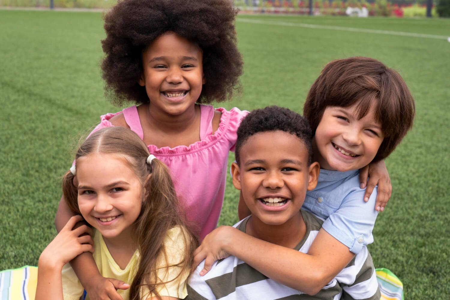 Grupo de crianças felizes sorrindo em um gramado, evidenciando o desenvolvimento facial saudável na Pleno Ser Odontologia em SBC
