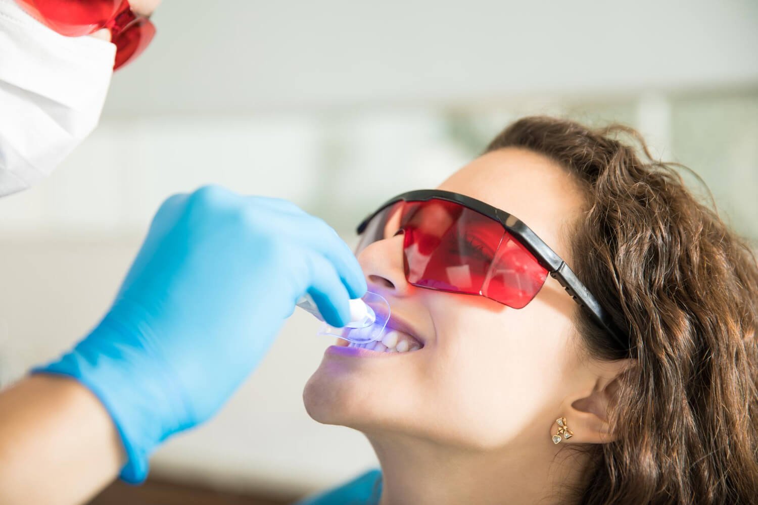 Dentista aplica laser de clareamento dental em paciente na Clínica Pleno Ser Odontologia em SBC. Procedimento seguro contra sensibilidade.