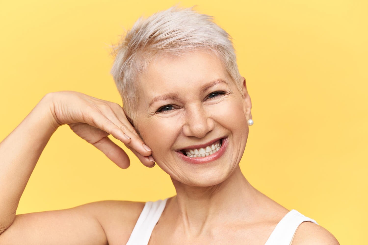 Mulher sênior sorri exibindo dentes brancos e bem alinhados após tratamento com facetas de porcelana na Pleno Ser Odontologia em SBC.